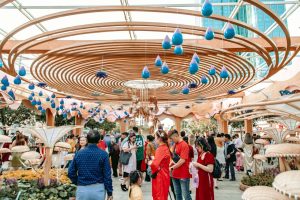 Colorful outdoor festival with intricate wooden ceiling design and bright blue raindrops.